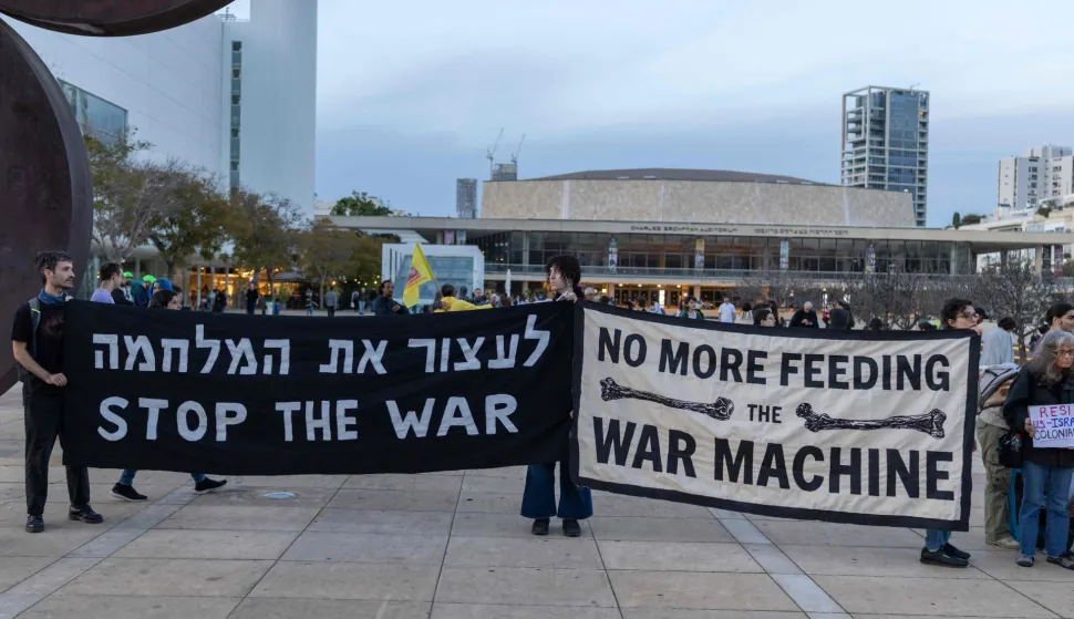 Demonstrators hold banners while gathering for the weekly anti-war protest at HaBima Square in Tel Aviv on March 28, 2026. The US and Israel launched strikes against Iran on February 28, sparking swift retaliation by the Islamic republic which responded with missile attacks across the region. (Photo by Ilia YEFIMOVICH/AFP)
