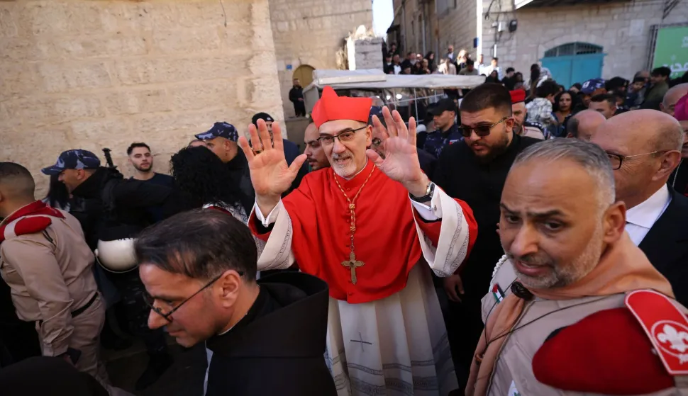 Latin Patriarch of Jerusalem Italian Pierbattista Pizzaballa is welcomed pilgrims, tourists and Palestinians as he arrive to lead the Christmas Mass in the Church of the Nativity in the Israeli-occupied West Bank city of Bethlehem, believed to be the birthplace of Jesus Christ, on December 24, 2025. Palestinian Scouts marched under a clear blue sky in Bethlehem on December 24, 2025, as the Palestinian city emerged from the shadow of the war in Gaza to celebrate its first festive Christmas in more than two years. Throughout the Gaza war that began with Hamas's attack on Israel in October 2023, a sombre tone marked Chistmases in Bethlehem, the biblical birthplace of Jesus Christ. (Photo by HAZEM BADER/AFP)