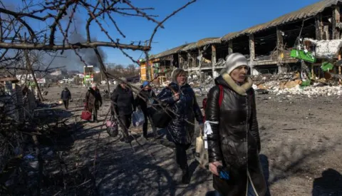 epa09814886 Residents coming from Bucha town, which is currently controlled by the Russian military, walk with luggage towards the Ukrainian checkpoint, at the frontline in Irpin town, Kyiv (Kiev) region, Ukraine, 10 March 2022. Thousands of residents are feeling Irpin and Bucha, as well as other settlements near Kyiv which were the most affected by the Russian army invasion. EPA/ROMAN PILIPEY