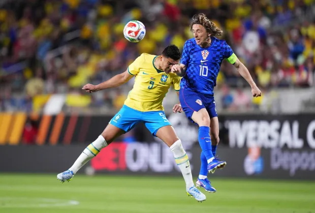 ORLANDO, FLORIDA - MARCH 31: Luka Modric of Croatia jumps for the ball with Richarlison of Brazil during the international friendly match between Brazil and Croatia at Camping World Stadium on March 31, 2026 in Orlando, Florida. Rich Storry/Getty Images/AFP (Photo by Rich Storry/GETTY IMAGES NORTH AMERICA/Getty Images via AFP)