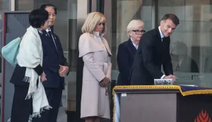 French President Emmanuel Macron (R) signs the guestbook during a visit at the War Memorial of Korea with his wife Brigitte Macron (C) and French Defence Minister Catherine Vautrin (2nd R) in Seoul on April 2, 2026. (Photo by Ludovic MARIN/POOL/AFP)