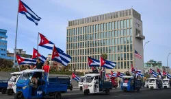 Cubans on electric tricycles decorated with Cuban flags ride past the US embassy during the anti-imperialist youth march in Havana on April 2, 2026. (Photo by YAMIL LAGE/AFP)
