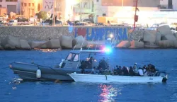 epa10870038 A small boat with migrants is escorted by an Italian patrol boat in the harbor of Lampedusa, Italy, 19 September 2023. According to Italy's Interior Ministry, nearly 126,000 immigrants and refugees have entered the country as of 2023, more than twice as many as during the same time period in 2022. EPA/CIRO FUSCO