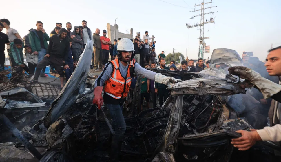First responders and Plestinians inspect a vehicle targered by an Israeli strike in Maghazi camp for Palestinian refugees in the central Gaza Strip on April 4, 2026. Since October 10, a fragile US-sponsored truce in Gaza has largely halted the fighting between Israeli forces and Hamas, but both sides have alleged frequent violations. (Photo by Eyad Baba/AFP)