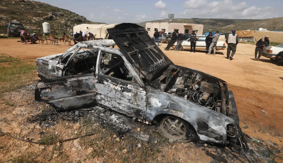 Palestinians stand near a vehicle that was destroyed following an Israeli settlers attack on the outskirts of Al-Lubban ash-Sharqiya village, south of Nablus in the occupied West Bank, on April 6, 2026. Violence more broadly in the West Bank, which Israel has occupied since 1967, has risen sharply since the October 7, 2023 Hamas attack on Israel triggered the Gaza war. It has continued despite a ceasefire in place since October 10. (Photo by JAAFAR ASHTIYEH/AFP)