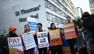 Staff members hold placards as they stand on a picket line during the first day of a six-day resident doctors' strike outside St Thomas' Hospital in central London on April 7, 2026. (Photo by Henry NICHOLLS/AFP)