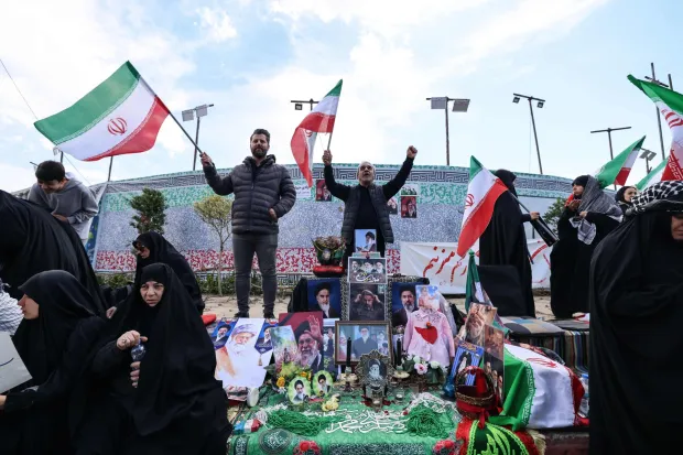 Iranians wave national flags next to a makeshift memorial as they gather in Tehran's Revolution Square after the United States and Iran agreed to a two-week ceasefire, on April 8, 2026. The United States and Iran agreed to a two-week ceasefire barely an hour before the US president's April 8 deadline to obliterate the country, triggering global relief alongside apprehension. (Photo by ATTA KENARE/AFP)/