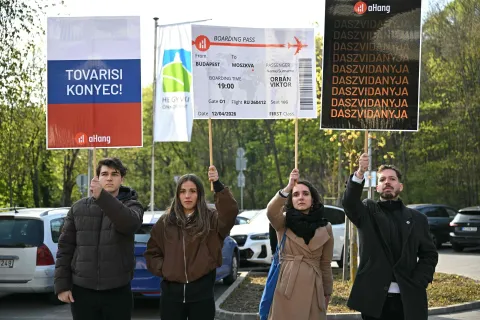 Opposition demonstrators hold up placards, among them one depicting a boarding pass for Hungarian Prime Minister Viktor Orban from Hungary to Moscow, as they protest in front of the polling station where Orban voted in Budapest on April 12, 2026. The vote could end Hungarian Prime Minister Viktor Orban's 16-year stint in power as the EU's longest serving current leader and a self-decribed "thorn" in the bloc's side. (Photo by Attila KISBENEDEK/AFP)