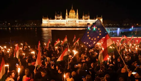 TOPSHOT - Supporters of the pro-European conservative TISZA party celebrate during the election night on the banks on the river Danube with the Parliament building in the background, in Budapest after the general election in Hungary, on April 12, 2026. Polls closed in Hungary's parliamentary election, with turnout reaching a record high in the crunch vote that sees nationalist Prime Minister Viktor Orban's 16-year stint in power face an unprecedented challenge from conservative political newcomer Peter Magyar. (Photo by Ferenc ISZA/AFP)