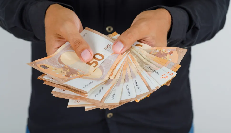 Young man in black shirt holding euro banknotes, front view.novac freepik