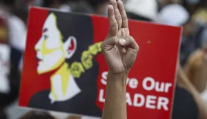 epa09022937 A protester flashes the defiant three-finger salute as another holds a placard calling for the release of detained Myanmar State Counselor Aung San Suu Kyi during a protest against the military coup, in Yangon, Myanmar, 19 February 2021. Mass protests against the military coup continued as new sanctions were imposed by Britain and Canada on the Myanmar military junta on 18 February for ousting the civilian government. EPA/NYEIN CHAN NAING