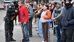 People stand outside a supermarket following a shooting in Kyiv on April 18, 2026. A gunman opened fire in Kyiv on April 18, 2026, killing at least five people, wounding others and taking hostages at a supermarket before being killed during an arrest attempt, officials said. Ukrainian President said that at least five people were dead and 10 hospitalised with wounds and trauma after the shooting in a residential district of the capital. (Photo by Sergei SUPINSKY/AFP)