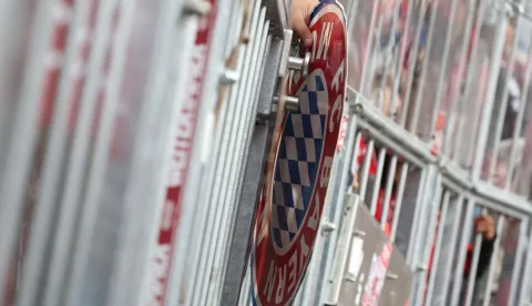 A fans hold an item with the colors of FC Bayern Munich through the fence of the terraces prior to the start of the German first division Bundesliga football match between FC Bayern Munich and VfB Stuttgart in Munich, southern Germany, on April 19, 2026. (Photo by Karl-Josef HILDENBRAND/AFP)/DFL REGULATIONS PROHIBIT ANY USE OF PHOTOGRAPHS AS IMAGE SEQUENCES AND/OR QUASI-VIDEO