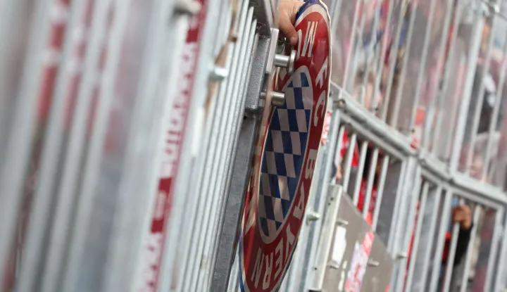 A fans hold an item with the colors of FC Bayern Munich through the fence of the terraces prior to the start of the German first division Bundesliga football match between FC Bayern Munich and VfB Stuttgart in Munich, southern Germany, on April 19, 2026. (Photo by Karl-Josef HILDENBRAND/AFP)/DFL REGULATIONS PROHIBIT ANY USE OF PHOTOGRAPHS AS IMAGE SEQUENCES AND/OR QUASI-VIDEO