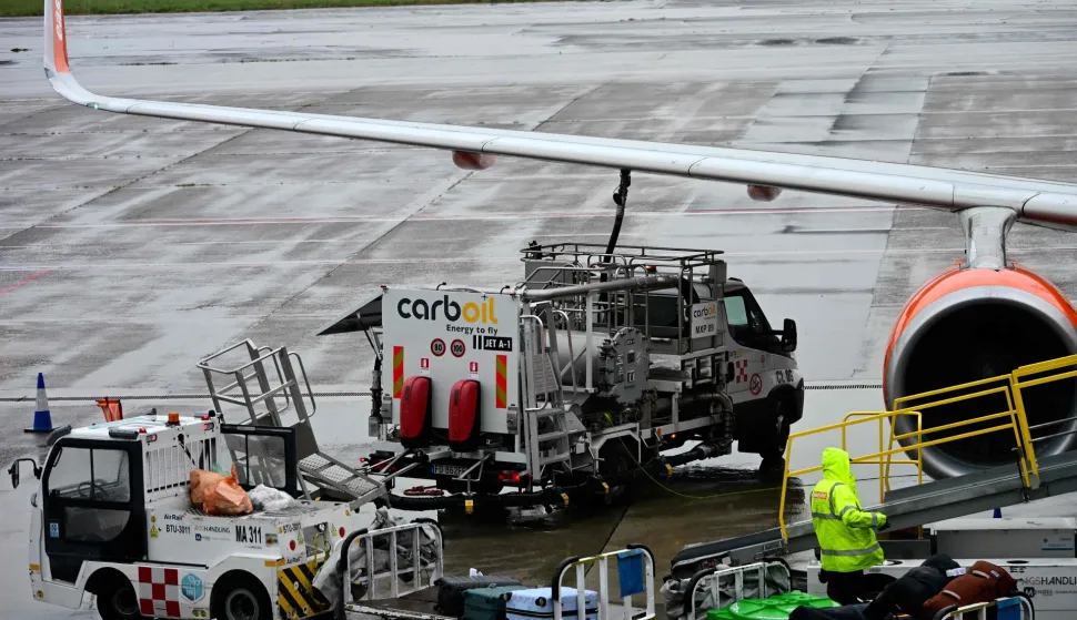 A worker loads luggage onto an Easyjet aircraft as a fuel truck "CarbOil" services the plane at Milan's Malpensa Airport on April 13, 2026. The European Commission said April 14, 2026 it fears Europe could face jet fuel supply issues "in the near future" with no end in sight to the Iran war roiling global energy markets. (Photo by Stefano Rellandini/AFP)