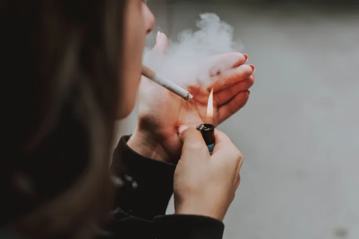 A selective closeup shot of a female lighting up a cigarette with a lightercigarete pu&scaron;enje ilustracija