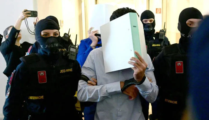 Two defendants in handcuffs are escorted to the courtroom by justice officers as a trial starts at court in Wiener Neustadt, Austria, on April 28, 2026, over a plot to attack a Taylor Swift concert in Vienna. The main suspect, who has been in detention since his arrest in August 2024, is facing terror offenses and other charges, prosecutors said. (Photo by ROLAND SCHLAGER/APA/AFP)/Austria OUT