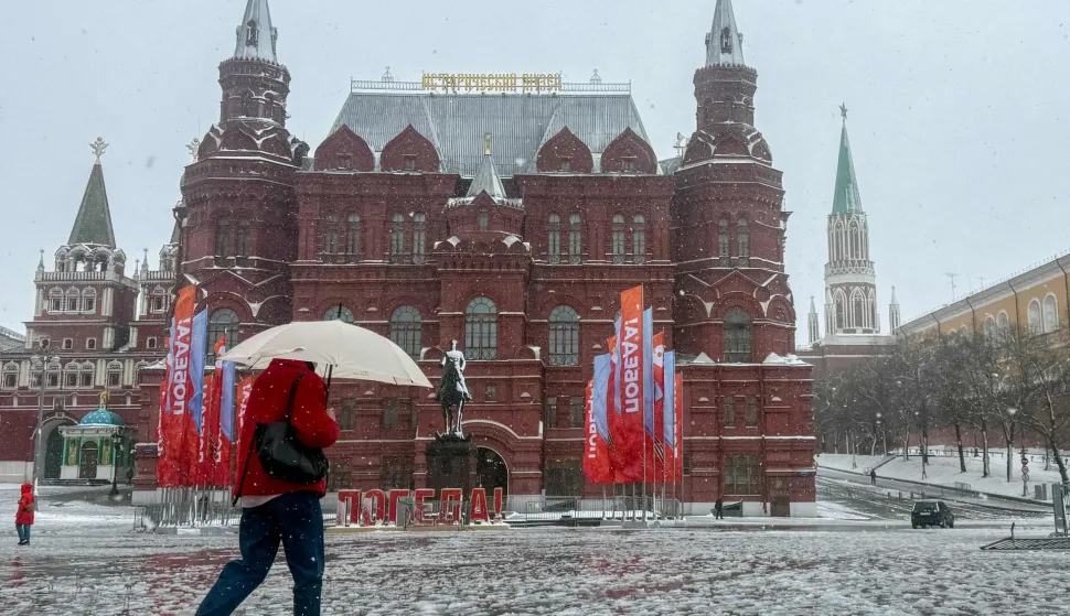 A person shelters from snow under an umbrella while walking outside the Kremlin during a snowstorm in Moscow on April 27, 2026. (Photo by Andrey BORODULIN/AFP)