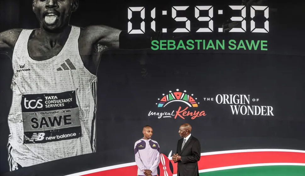 Kenya's President William Ruto (R) congratulates Kenyan marathon runner Sebastian Sawe (L) on stage during a ceremony at State House in Nairobi, on April 30, 2026, after breaking a historic world record at the London Marathon. Sebastian Sawe became the first man to run under two hours for a marathon in race conditions thanks to extraordinary talent, a punishing training regime, and the lightest shoes in history. In London on April 26, 2026, the 31-year-old Kenyan achieved one of sport's milestones, ranking alongside Roger Bannister's first sub-four minute mile in 1954. (Photo by Luis TATO/AFP)