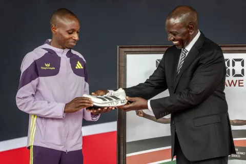Kenyan marathon runner Sebastian Sawe (L) gifts one of the shoe he used to break the world record at the London Marathon to Kenya's President William Ruto (R) during a congratulatory ceremony at State House in Nairobi, on April 30, 2026. Sebastian Sawe became the first man to run under two hours for a marathon in race conditions thanks to extraordinary talent, a punishing training regime, and the lightest shoes in history. In London on April 26, 2026, the 31-year-old Kenyan achieved one of sport's milestones, ranking alongside Roger Bannister's first sub-four minute mile in 1954. (Photo by Luis TATO/AFP)