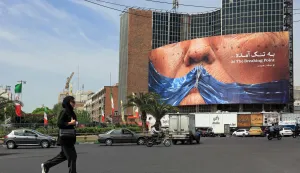 A woman walks past an anti-US billboard referring to President Donald Trump and the Strait of Hormuz, installed on a building at the Valiasr Square in Tehran on May 2, 2026. A senior Iranian military officer said on May 2 that renewed fighting between the US and Iran was "likely", hours after President Donald Trump said he was "not satisfied" with a new Iranian negotiating proposal. (Photo by AFP)/