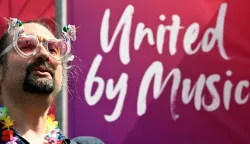 A man cheers prior to the opening ceremony of the Eurovision Song Contest 2026 at the City Hall Square in Vienna, Austria on May 10, 2026. The "Turquoise Carpet" event is the official starting point of Eurovision week in Vienna. The Austrian capital will host the two semi-finals on May 12 and May 14 and the final on May 16, 2026. (Photo by Tobias SCHWARZ/AFP)