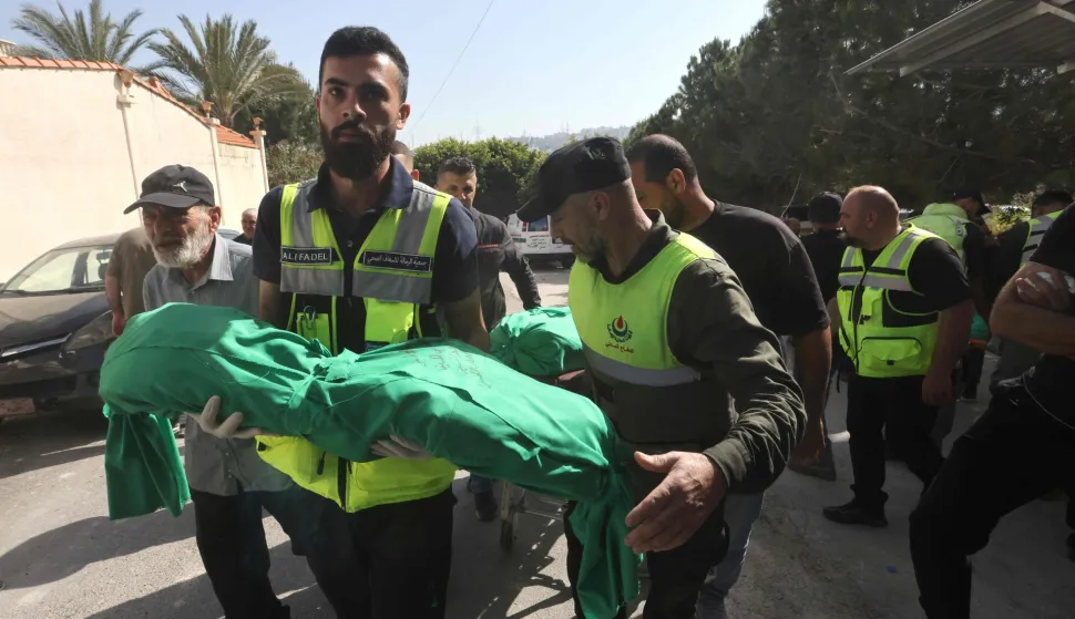 A Lebanese Civil Defence volunteer and his colleagues deliver the shrouded bodies of nine people killed the day before in an Israeli airstrike on the southern Lebanese village of Jibshit, during their funeral in the city of Sidon on May 10, 2026. Israel carried out strikes across Lebanon on May 9, 2026, killing at least nine people in the south according to authorities, with raids also targeting a highway not far from Beirut outside of Hezbollah's traditional strongholds. Lebanon was drawn into the Middle East war on March 2 when Tehran-backed militant group Hezbollah launched attacks on Israel to avenge the killing of the Iranian leader. Israel has responded with broad strikes across Lebanon and a ground offencive. (Photo by MAHMOUD ZAYYAT/AFP)