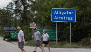OCHOPEE, FLORIDA - APRIL 22: People walk near the front entrance to the immigration detention center in the Florida Everglades known as ?Alligator Alcatraz" on April 22, 2026, in Ochopee, Florida. A federal appeals court overturned an injunction by a district court judge requiring officials to dismantle ?Alligator Alcatraz? in response to a lawsuit filed by environmental groups. Joe Raedle/Getty Images/AFP (Photo by JOE RAEDLE/GETTY IMAGES NORTH AMERICA/Getty Images via AFP)