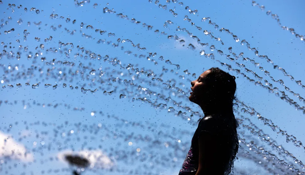epaselect epa11455608 Caroline Gilligan cools off in a water fountain in the Georgetown Waterfront in Washington, DC, USA, 03 July 2024. The DC area is bracing for another heat wave, with temperatures for much of the coming week expected to be in the mid-90s Fahrenheit (35 degrees Celsius). EPA/JIM LO SCALZO