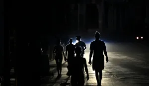 People walk on a street during a blackout in Havana on May 13, 2026. Cuba blamed the United States for the "particularly tense" situation in its power grid on May 13, 2026, which has been plagued by prolonged blackouts, while Washington once again offered 0 million in aid to the island. (Photo by Yamil LAGE/AFP)
