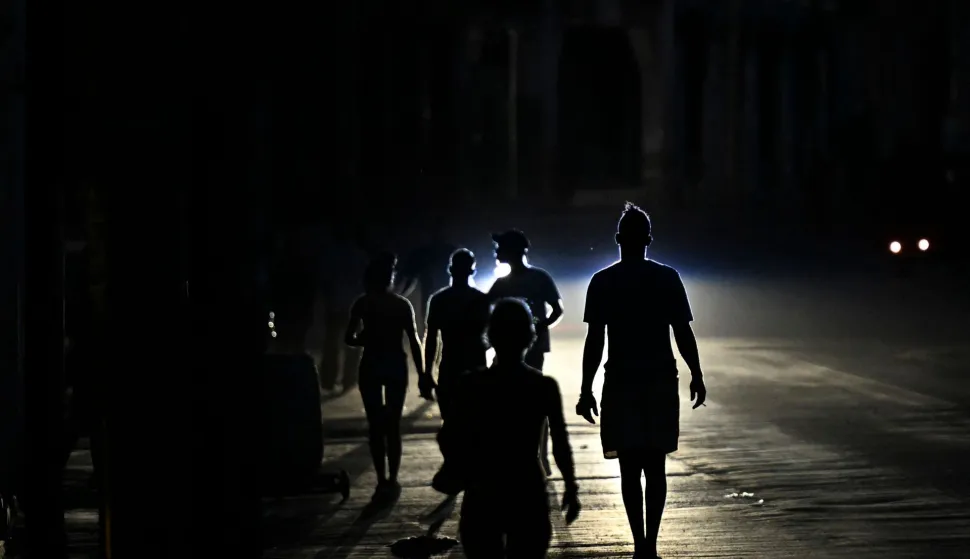 People walk on a street during a blackout in Havana on May 13, 2026. Cuba blamed the United States for the "particularly tense" situation in its power grid on May 13, 2026, which has been plagued by prolonged blackouts, while Washington once again offered $100 million in aid to the island. (Photo by Yamil LAGE/AFP)