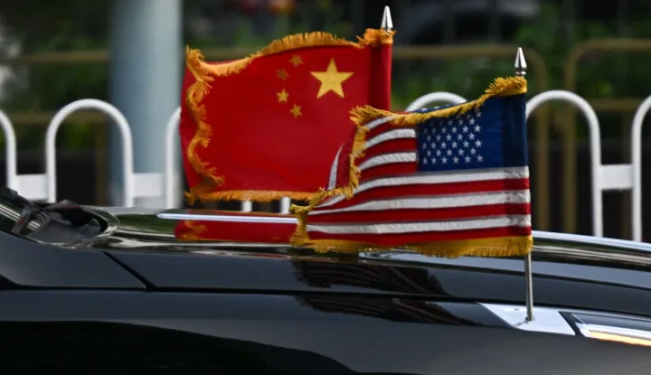 The US and China flags are seen on a vehicle in the motorcade of US President Donald Trump as it leaves the hotel in Beijing on May 14, 2026. (Photo by Pedro PARDO/AFP)
