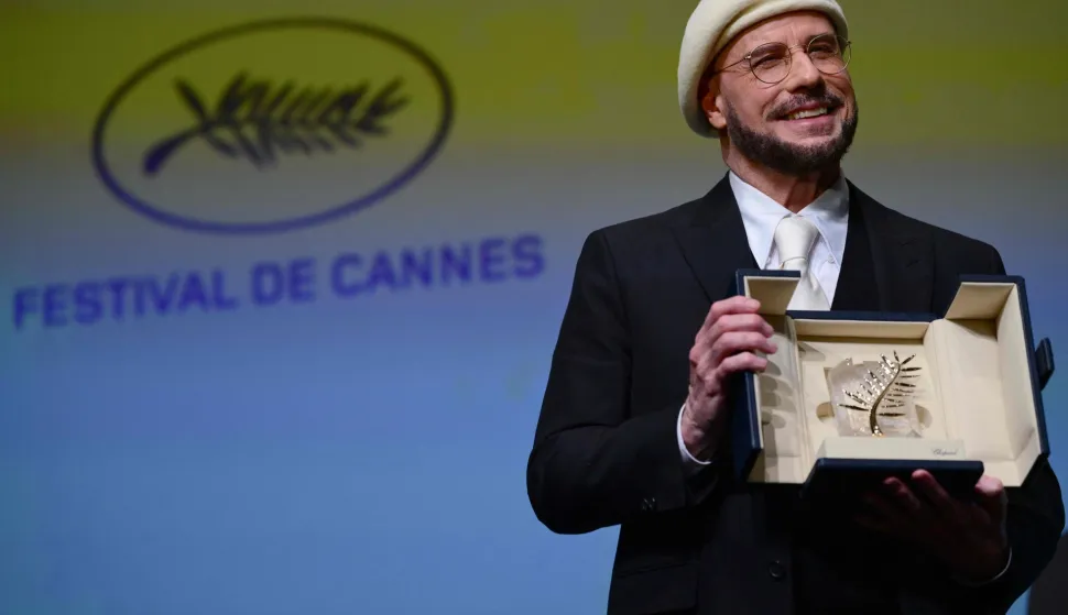 US director, screenwriter and writer John Travolta (L) receives an honorary Palm d'Or award prior to the screening of the film "Propeller One-Way Night Coach" at the 79th edition of the Cannes Film Festival in Cannes, southern France on May 15, 2026. (Photo by Olivier CHASSIGNOLE/AFP)