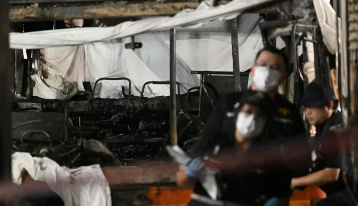 Forensic officers investigate the site of a train collision with a bus (back) underneath Makkasan Airport Rail station in Bangkok on May 16, 2026. A collision between a freight train and a bus killed at least eight people and injured more than 30 in the Thai capital Bangkok, emergency services said. (Photo by Lillian SUWANRUMPHA/AFP)