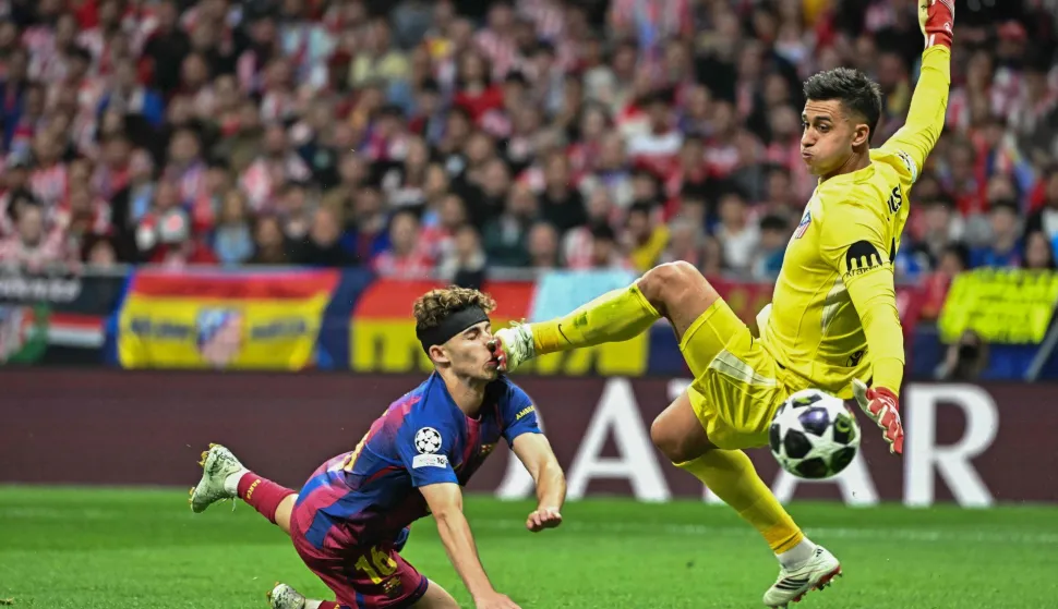 Barcelona's Spanish midfielder #16 Fermin Lopez (L) collides with Atletico Madrid's Argentine goalkeeper #01 Juan Musso during the UEFA Champions League quarter final second leg football match between Club Atletico de Madrid and FC Barcelona at Metropolitano Stadium in Madrid on April 14, 2026. (Photo by Javier SORIANO/AFP)