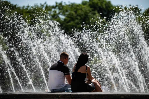 A couple sits in front of a fountain at the foot of the TV Tower as temperatures rose to 26 degrees Celsius in Berlin on May 29, 2026. (Photo by John MACDOUGALL/AFP)
