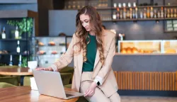 Business Woman Restaurant Owner Use Laptop In Hands Dressed Elegant Pantsuit Sitting On Table In Restaurant With Bar Counter Background Caucasian Female Business Person Indoor; Shutterstock ID 2237923749; purchase_order-; job-; client-; other: