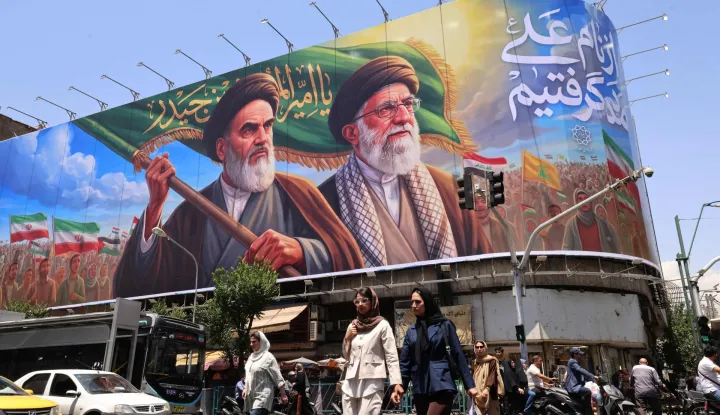 TOPSHOT - People cross the street past a large billboard showing portraits of Iran's late supreme leader, Ayatollah Ruhollah Khomeini (L) and slain supreme leader Ayatollah Ali Khamenei (R) in central Tehran on June 8, 2026. Iran said on June 8 that the resumption of hostilities in the Middle East war will have consequences for ongoing talks with the United States to reach peace in the region. "It is perfectly natural that the diplomatic process initiated to put an end to this imposed war would be affected," Iranian foreign ministry spokesman Esmaeil Baqaei said at a press conference in Tehran. (Photo by ATTA KENARE/AFP)/