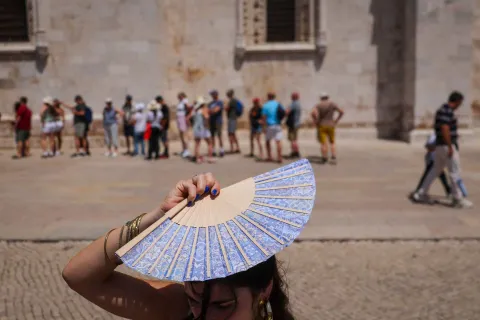 (FILES) A woman shades her head with a fan in front of Jeronimos Monastery in Belem, during a heatwave in Lisbon on May 27, 2026. To face the intensity of the record-breaking heatwave scorching Europe, people are turning to makeshift solutions to stay cool. (Photo by PATRICIA DE MELO MOREIRA/AFP)