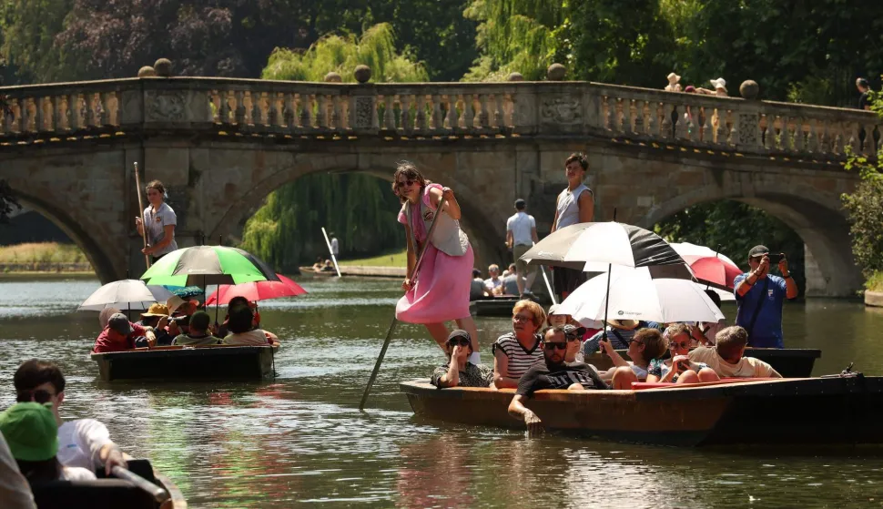 (FILES) People shelter from the sun beneath parasols as they take a punt ride along the River Cam, during a heatwave, in Cambridge on June 24, 2026. According to the the World Weather Attribution group of scientists, human-caused climate change is "unequivocally" responsible for the intensity of a record-breaking heatwave scorching Europe. It would have been "virtually impossible" for such exceptional temperatures to occur in June fifty years ago. (Photo by Chris RADBURN/AFP)
