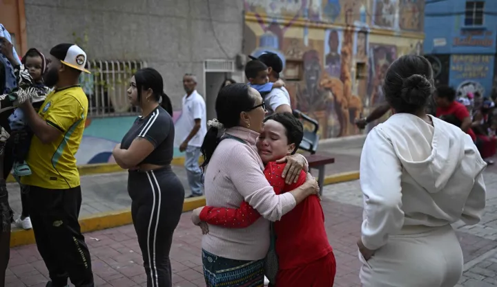 TOPSHOT - A woman comforts a child in the street following an earthquake in Caracas on June 24, 2026. Two earthquakes of magnitude 7.2 and 7.5 struck the same area of Venezuela on the evening of June 24, causing buildings to collapse, according to the United States Geological Survey (USGS) and AFP journalists. The quakes drove residents of the capital, Caracas, into the streets. (Photo by Federico PARRA/AFP)
