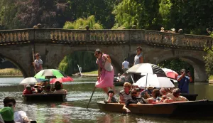 (FILES) People shelter from the sun beneath parasols as they take a punt ride along the River Cam, during a heatwave, in Cambridge on June 24, 2026. According to the the World Weather Attribution group of scientists, human-caused climate change is "unequivocally" responsible for the intensity of a record-breaking heatwave scorching Europe. It would have been "virtually impossible" for such exceptional temperatures to occur in June fifty years ago. (Photo by Chris RADBURN/AFP)
