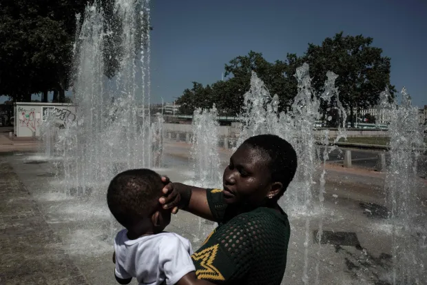 (FILES) People cool off in a fountain in Lyon on May 27, 2026 as a heatwave hits France. To face the intensity of the record-breaking heatwave scorching Europe, people are turning to makeshift solutions to stay cool. (Photo by Jeff PACHOUD/AFP)