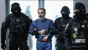 Judicial officers escort Saudi Arabian defendant Taleb Al Abdulmohsen (2nd L) to the courtroom upon his arrival on June 26, 2026 in Magdeburg, eastern Germany, before his trial for driving an SUV through a crowd at a Christmas market. The court sentenced to life in jail the Saudi psychiatrist who drove an SUV through a crowded Christmas market in 2024, killing six people and injuring more than 300. (Photo by Ronny HARTMANN/AFP)