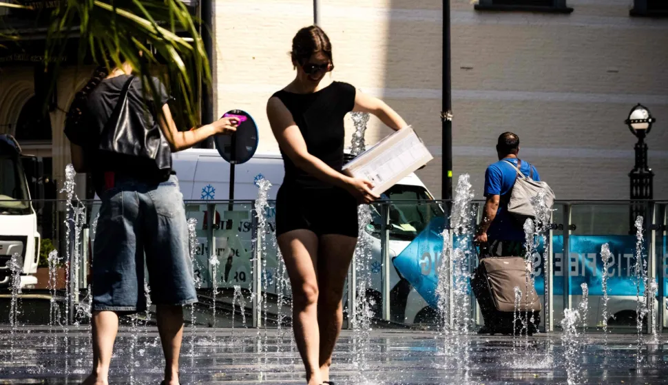 People try to cool off in a fountain in the centre of Tilburg on June 25, 2026 during a heatwave in Europe. A code orange warning is in effect in the central and southern Netherlands due to extreme heat. At least 101 million Europeans were expected to experience temperatures of over 35C on June 25, 2026, in a punishing and increasingly deadly heatwave hotter than weather in parts of Africa. (Photo by ROB ENGELAAR/ANP/AFP)/Netherlands OUT