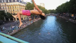 A youth jump from a bridge into the Canal Saint-Martin as France experiences a heatwave, in Paris on June 25, 2026. Due to the ongoing heatwave sweeping across France - the Bassin des Recollets - a portion of the Canal Saint-Martin in the French capital has been opened for swimming from June 17. (Photo by Ludovic MARIN/AFP)