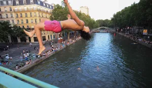 A youth jump from a bridge into the Canal Saint-Martin as France experiences a heatwave, in Paris on June 25, 2026. Due to the ongoing heatwave sweeping across France - the Bassin des Recollets - a portion of the Canal Saint-Martin in the French capital has been opened for swimming from June 17. (Photo by Ludovic MARIN/AFP)