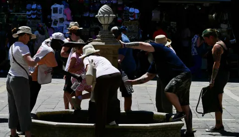 People fill bottles from a public water fountain during a heatwave in Venice on June 27, 2026. (Photo by Stefano RELLANDINI/AFP)