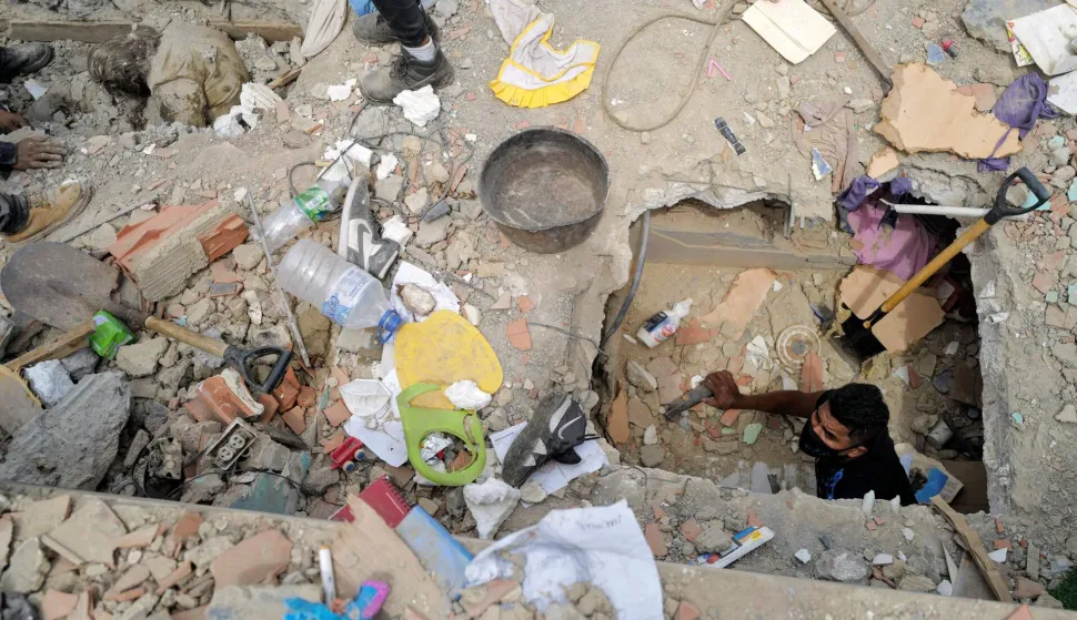 A volunteer searches for victims as others (L, top) try to retrieve a body from the rubble in Caraballeda, La Guaira State, Venezuela on June 28, 2026, following the June 24 twin earthquakes. (Photo by Mauricio VALENZUELA/AFP)