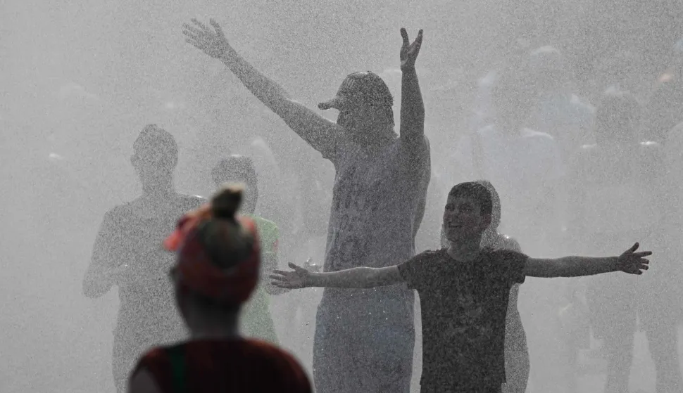 Police use water cannon to spray people with water as the arrive at the Olympic stadium for a concert of US singer Bruno Mars on June 28, 2026, in Berlin, as the German capital is expected to reach temperatures around 40 degrees Celsius during a heatwave in Europe. Tens of millions are braving a weekend of extreme temperatures in Europe as a deadly heatwave moves eastwards, with some countries announcing rising death tolls and health services warning of saturation. While some mild relief is expected Sunday in western Europe, German forecasters are warning that more temperature records could still be broken over the weekend as eastern countries issue a slew of red alerts for the coming days. (Photo by RALF HIRSCHBERGER/AFP)